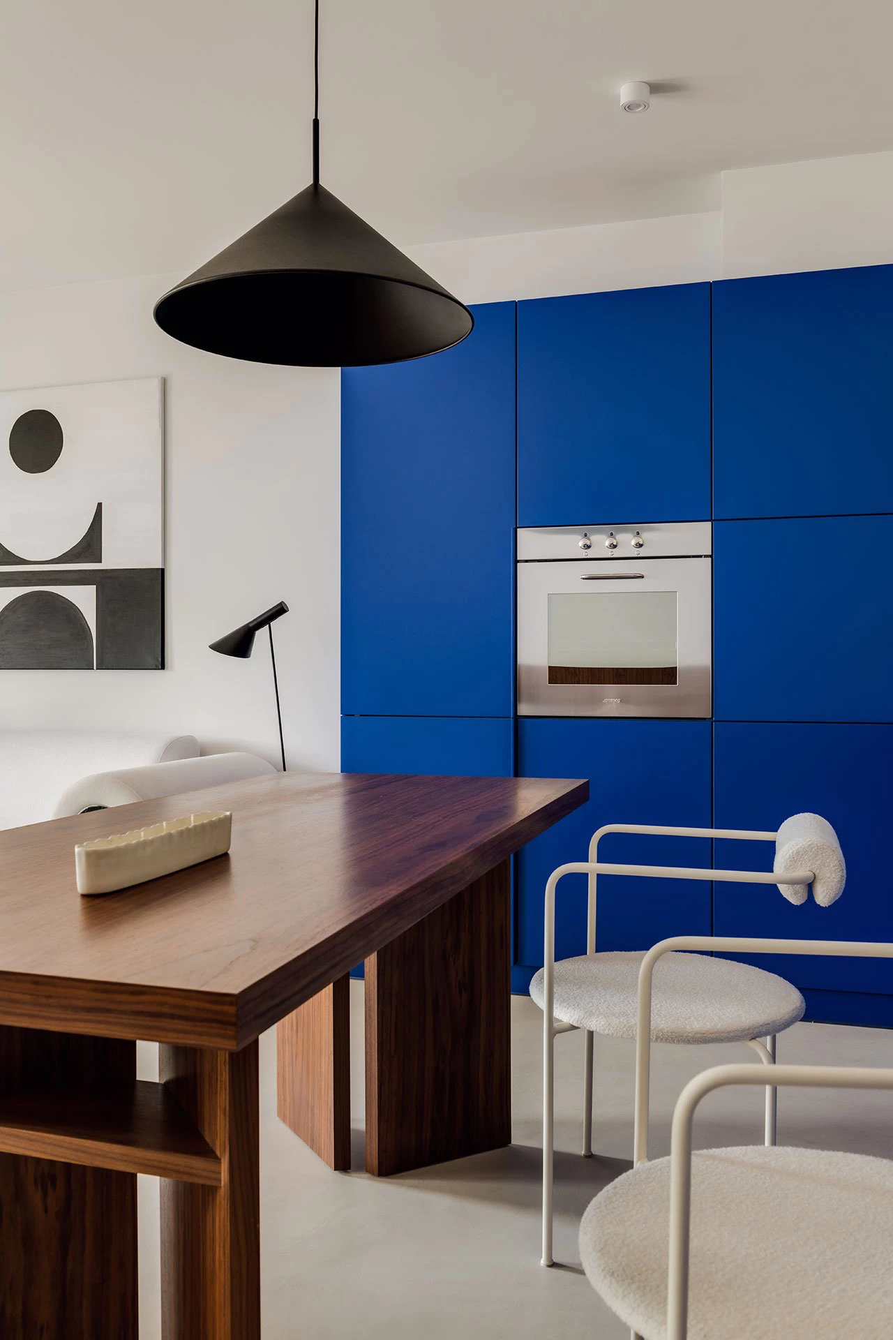 Modern kitchen with bold blue cabinets and walnut dining table